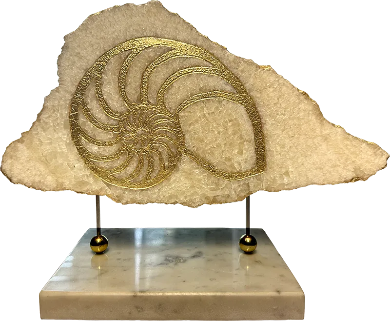 Golden Nautilus, natural state — golden spiral engraved in pearl onyx, suspended on stainless-steel supports over a Bianco di Carrara marble base